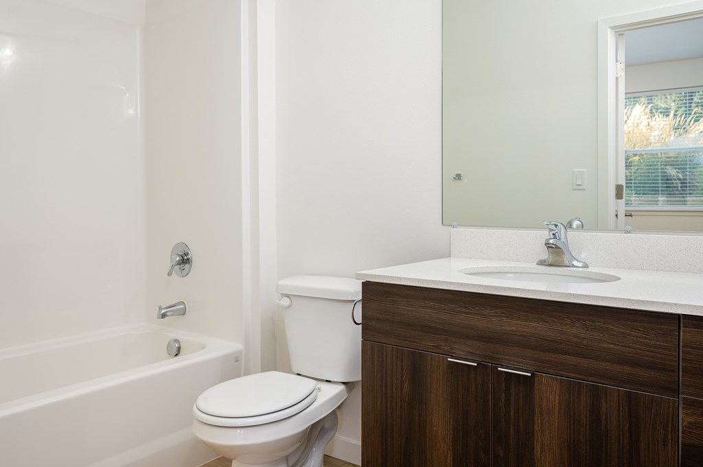 A white toilet sits next to a bathtub in a bathroom.