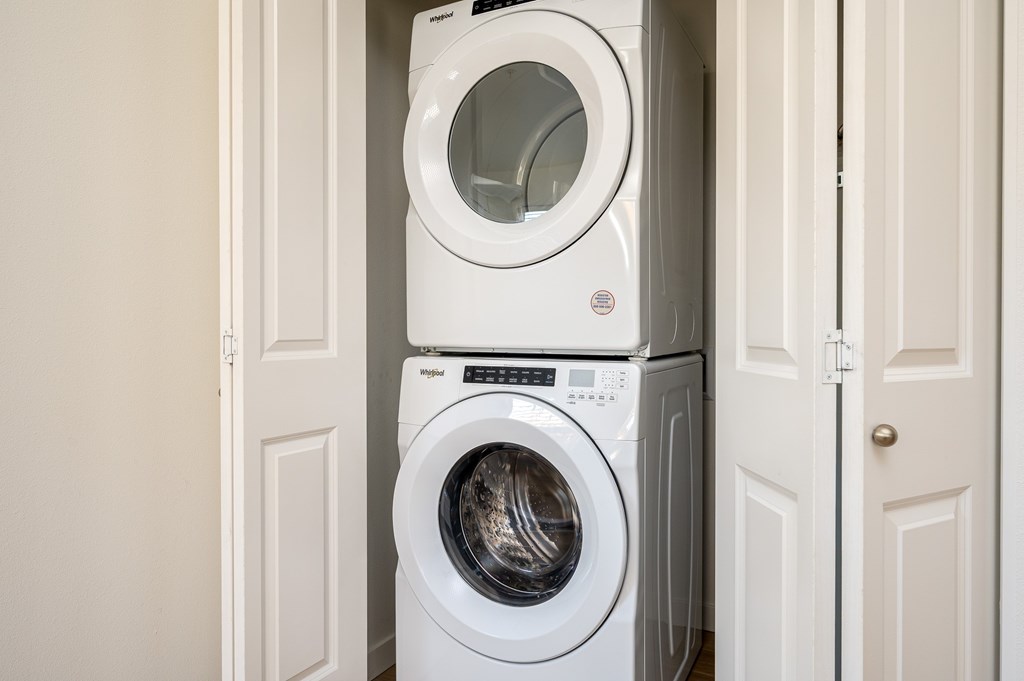 A white washing machine and dryer stacked on top of each other in a laundry room.