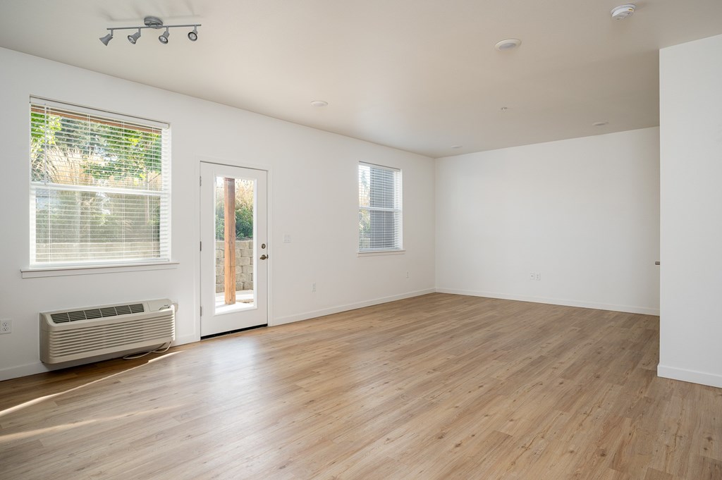 A room with a wooden floor and a window with blinds.