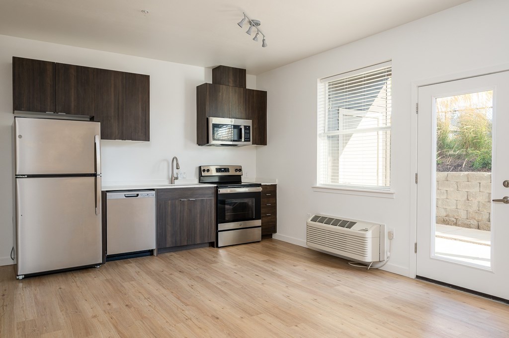 A kitchen with a refrigerator, oven, and microwave.