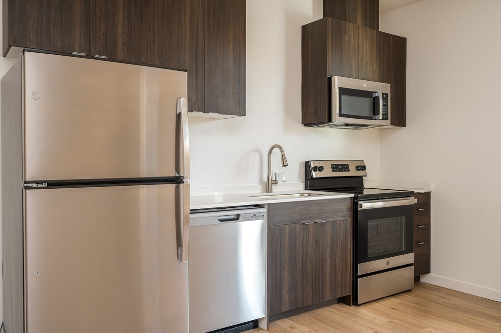 A modern kitchen with a stainless steel refrigerator, microwave, oven, and dishwasher.