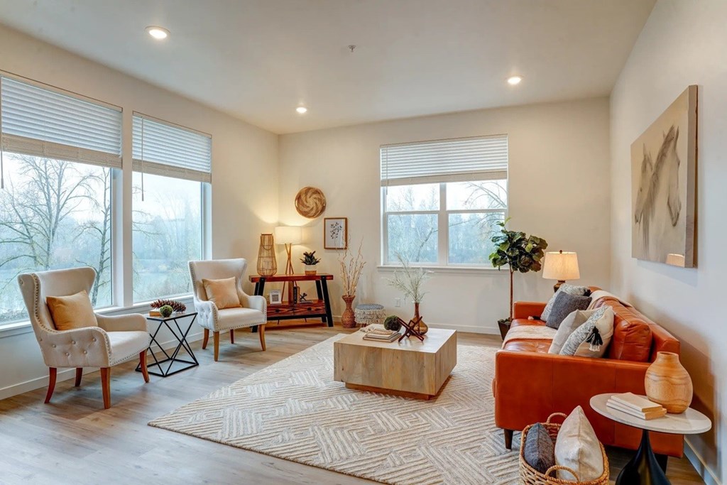 A living room with a red couch, a wooden coffee table, and a large window with blinds.