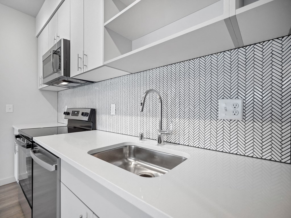 an all white kitchen with a sink and a stove and a microwave