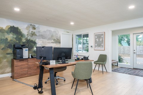 A room with a desk, chairs, and a computer setup.