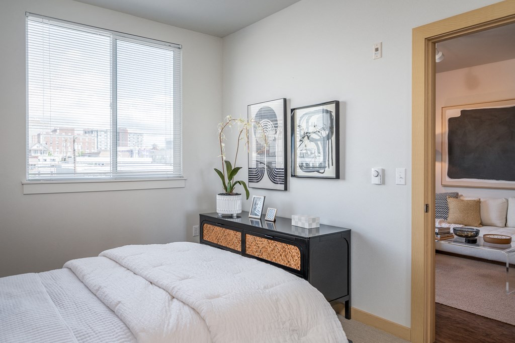 One Bedroom Apartments in Everett WA - The Waterline - Bedroom with Vinyl Hardwood Flooring, Area Rug, Stylish Decor, and Sliding Doors to the Balcony