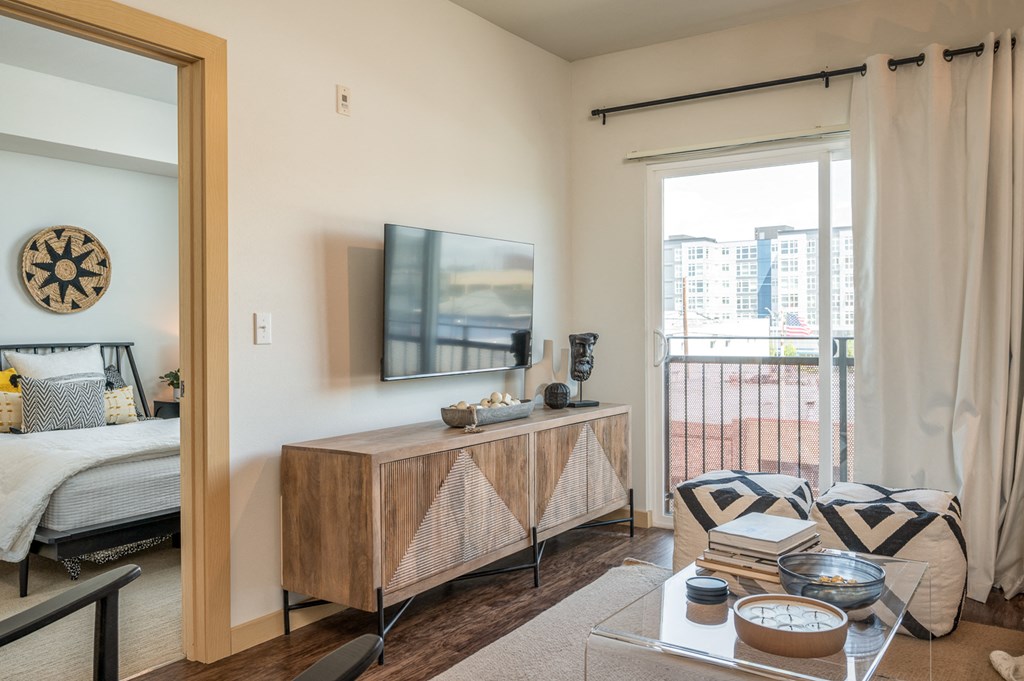One Bedroom Apartments in Everett WA - The Waterline - Bedroom with Vinyl Hardwood Flooring, Area Rug, Stylish Decor, and Sliding Doors to the Balcony