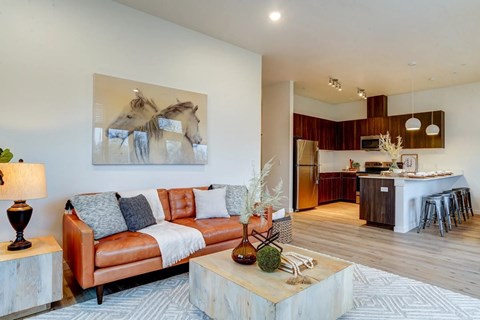 A living room with a couch, a coffee table, and a painting of horses on the wall.