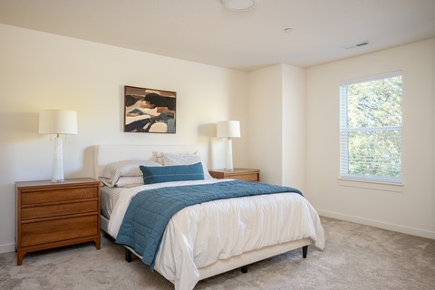 A bedroom with a bed, nightstands, and a painting on the wall.