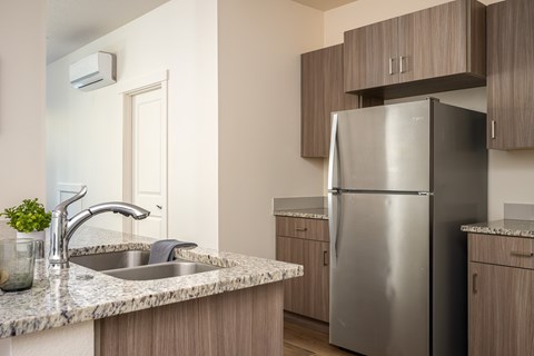 A kitchen with a stainless steel refrigerator and a marble countertop.