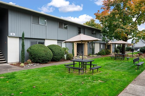 A grey building with a patio table and chairs in front of it.