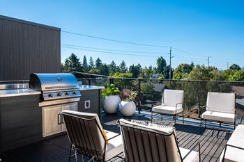a deck with a grill and chairs on a roof