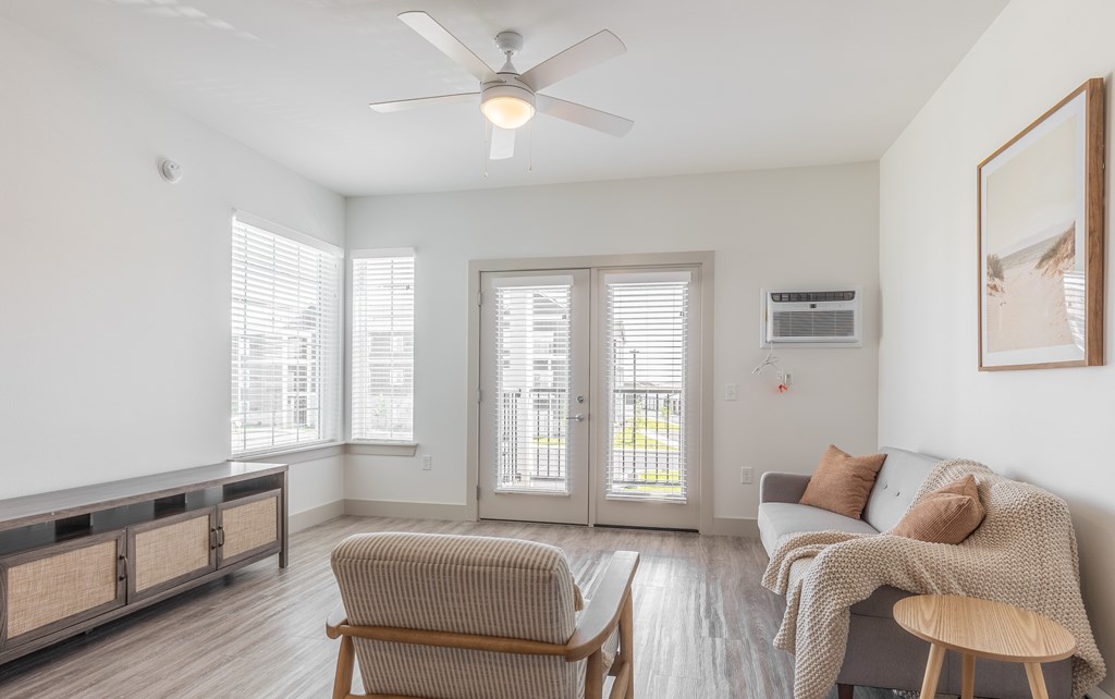 A living room with a grey couch, a wooden chair, and a ceiling fan.