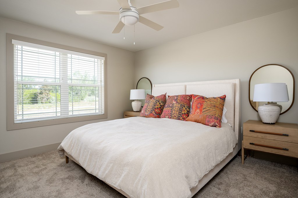 A bedroom with a white bed and a ceiling fan.