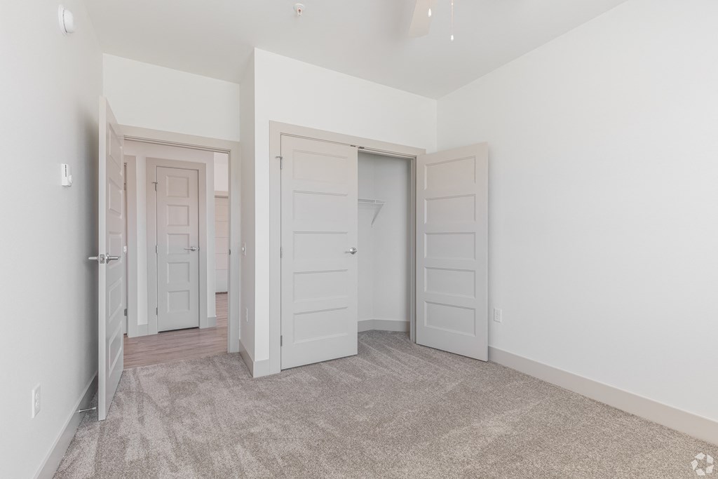 a bedroom with white walls and doors and a carpeted floor