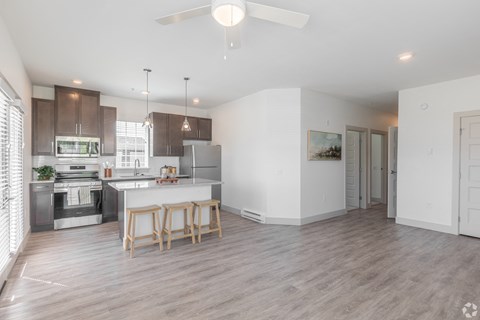 a living room with a kitchen and a ceiling fan
