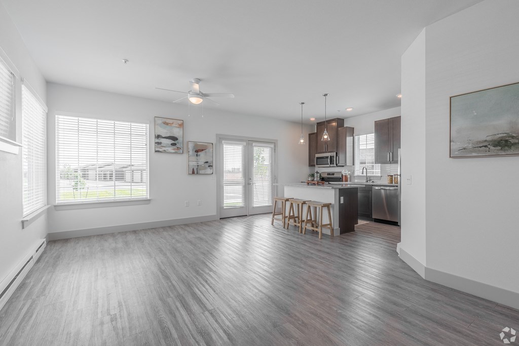 a living room and kitchen with wood flooring and a large window