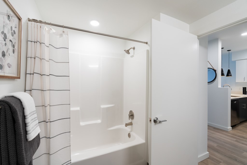 A white bathroom with a shower and a towel hanging on the side.