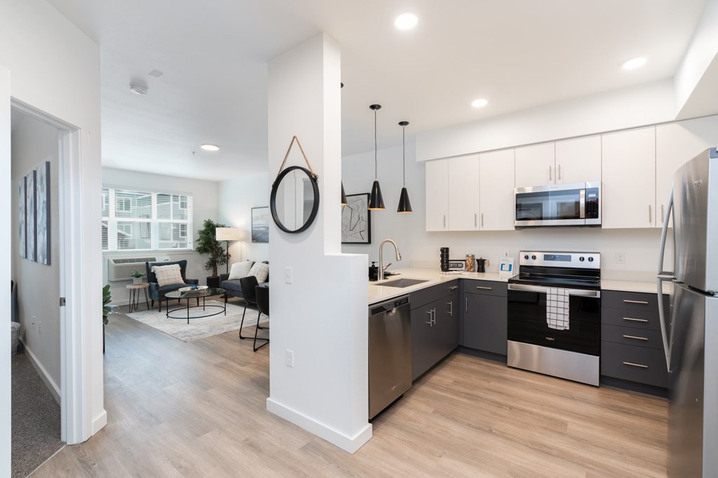 A modern kitchen with stainless steel appliances and a dining area with chairs and a table.