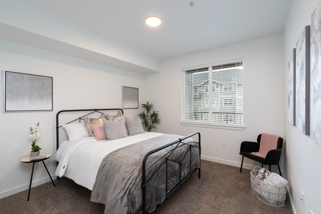 A bedroom with a bed, chair, and a window with blinds.