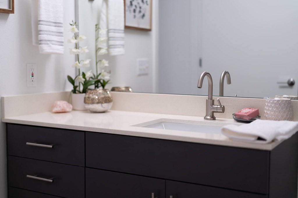 A bathroom sink with a white counter top and a silver faucet.