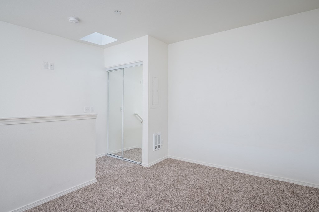 a bedroom with white walls and carpet and a sliding glass door