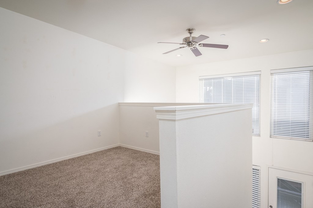 an empty room with a ceiling fan and a window