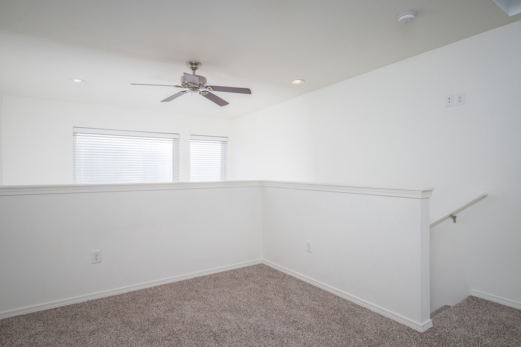 a bedroom with white walls and a ceiling fan