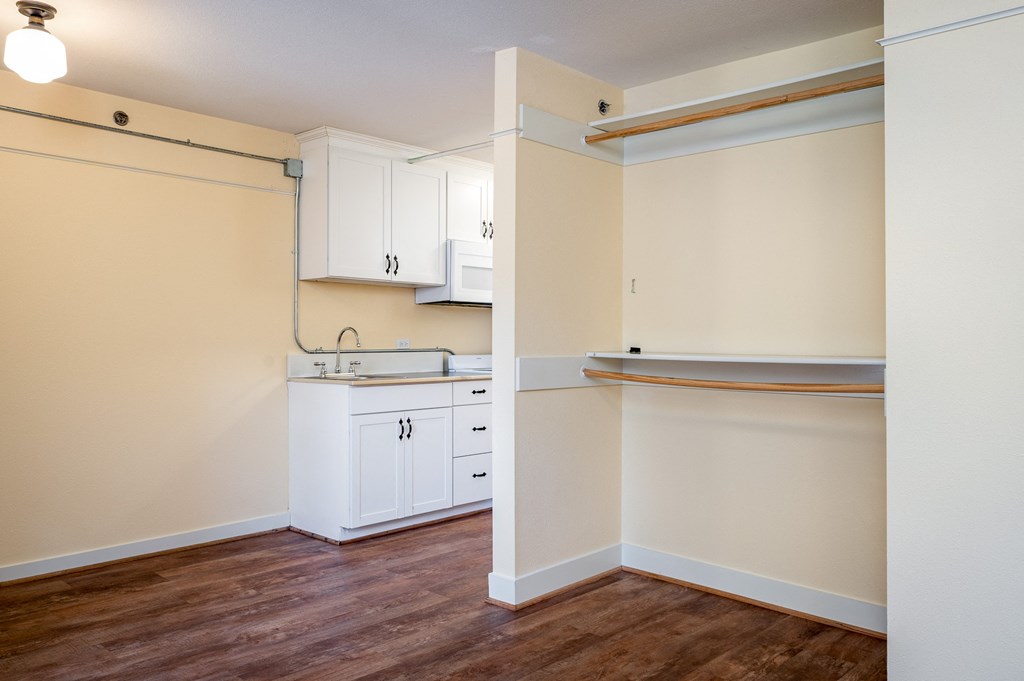 a kitchen with white cabinets and a wooden floor