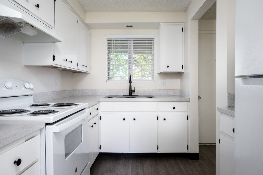 a kitchen with white cabinets and white appliances and a window