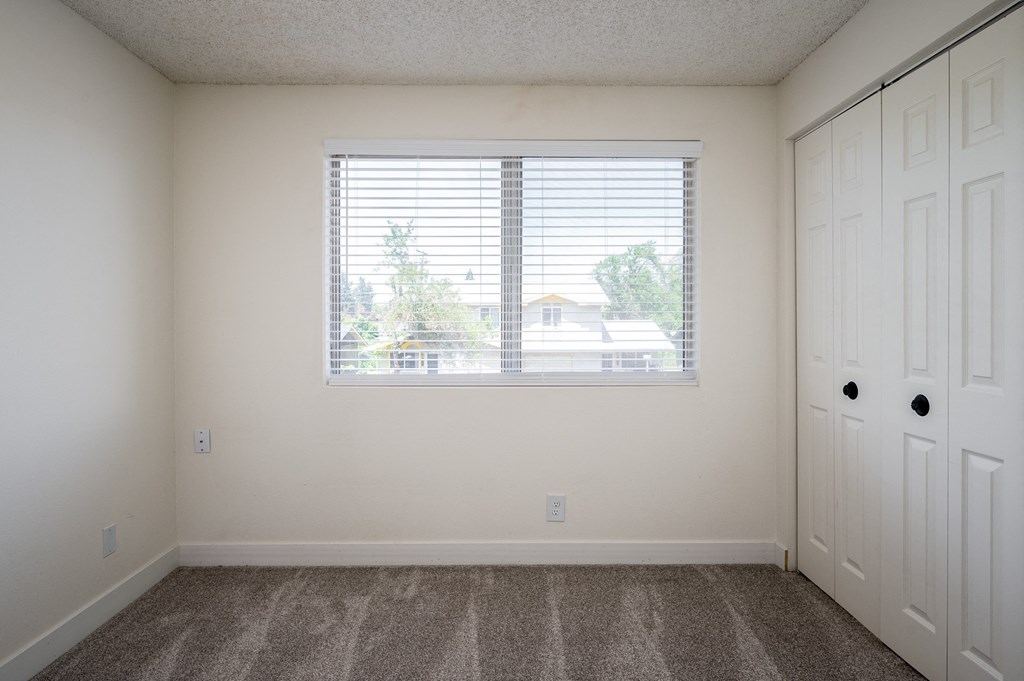 an empty bedroom with a large window and white doors