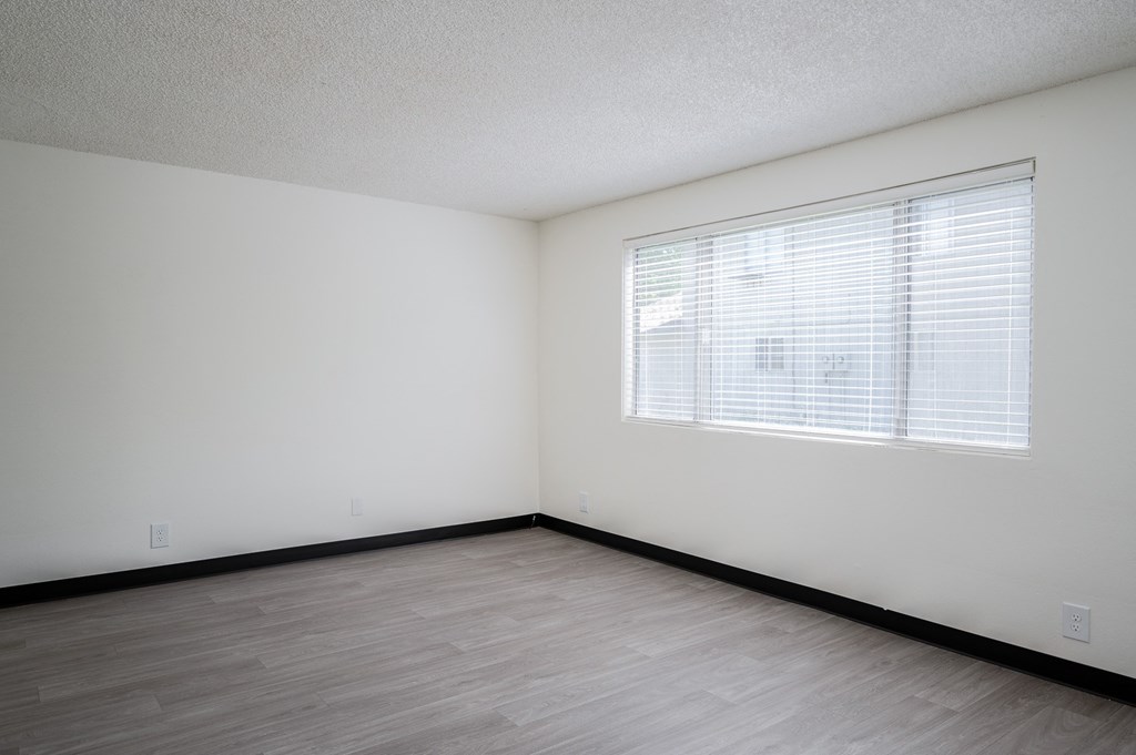 the spacious living room of an empty apartment with a large window