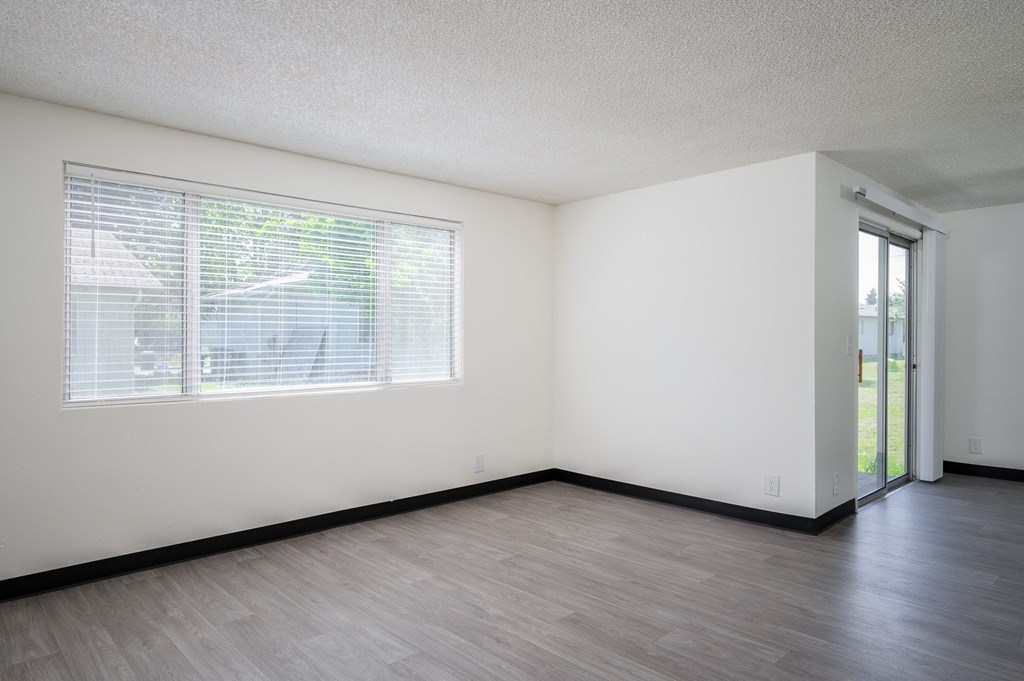 the living room of an empty apartment with a large window and wood floors