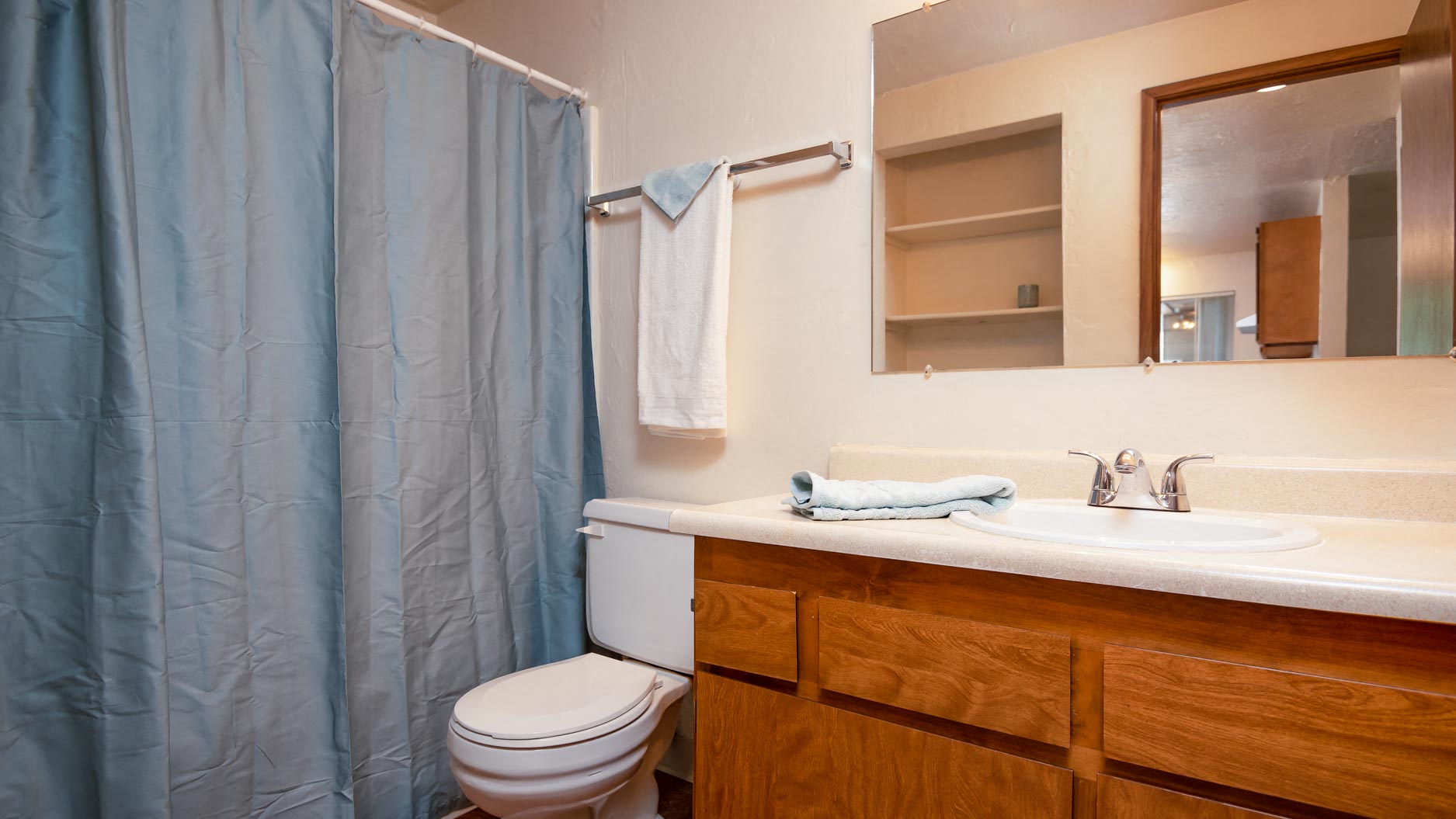 Broadway Center | Bathroom with Wood Cabinetry and Large Mirror