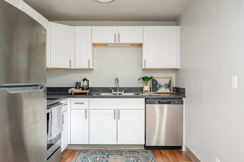A kitchen with white cabinets and a stainless steel refrigerator.