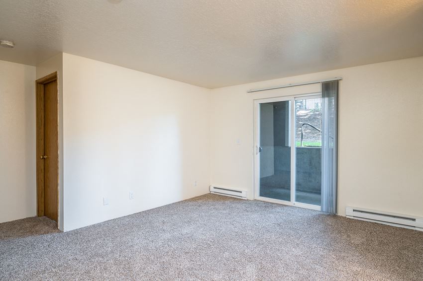 an empty living room with a sliding glass door to a patio
