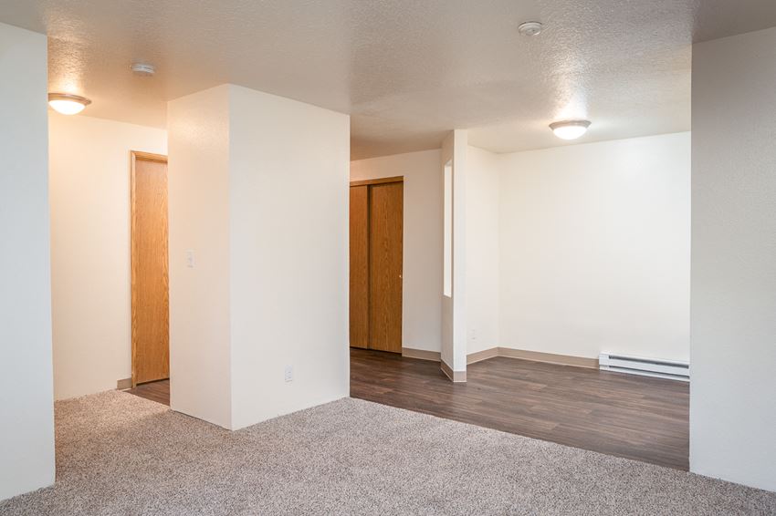 an empty living room with wood flooring and white walls