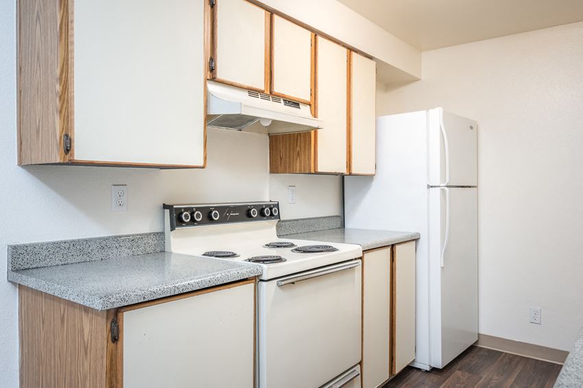 an empty kitchen with white appliances and wood cabinets