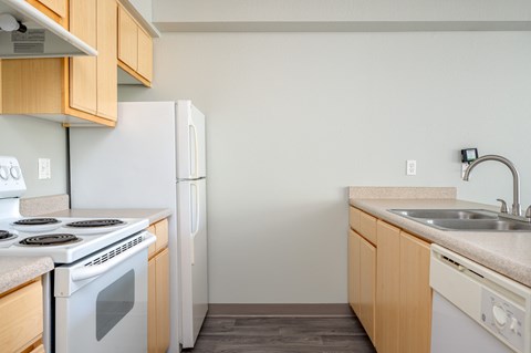 A kitchen with a white stove and white refrigerator with wooden cabinets.