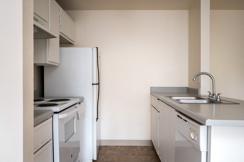 an empty kitchen with a stove refrigerator and sink