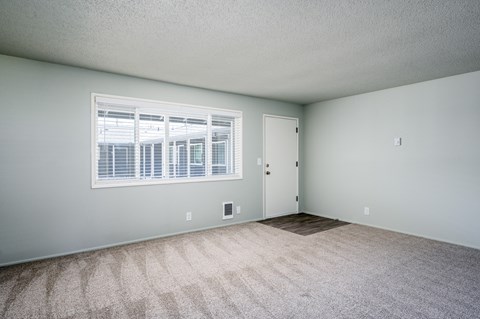 the spacious living room of an apartment with a large window
