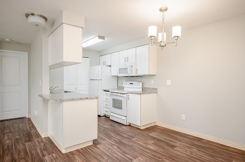 A kitchen with white cabinets and a wooden floor.