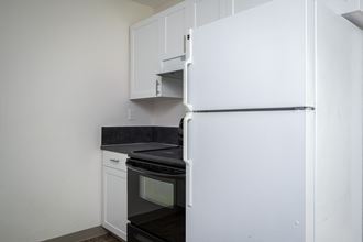 a kitchen with a refrigerator and stove and white cabinets