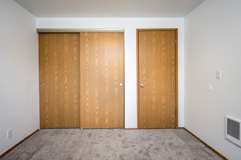 Two brown doors in a room with carpeted floor.