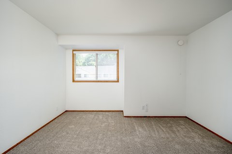 A room with a window and carpeted floor.
