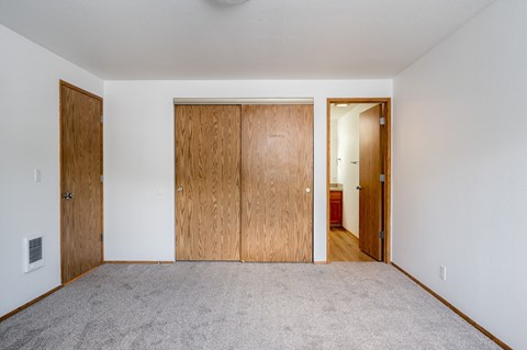 A room with a carpeted floor and three wooden doors.
