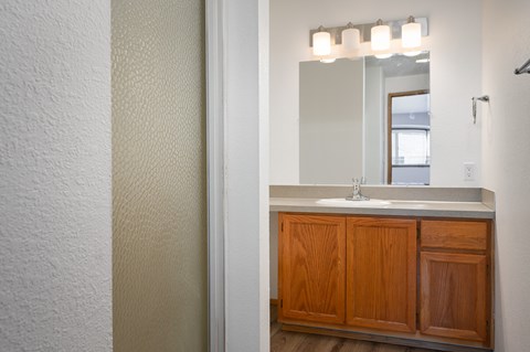A bathroom with a sink and wooden cabinets.