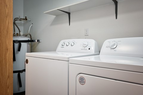 Two white washing machines in a laundry room.