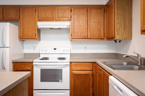A kitchen with wooden cabinets and a white stove top oven.