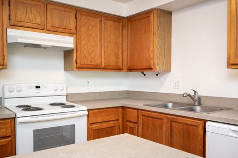 A kitchen with wooden cabinets and a white stove top oven.