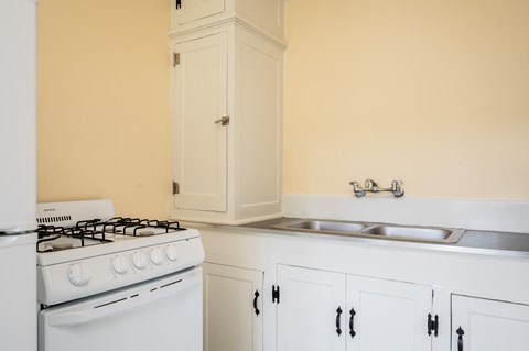 a kitchen with a stove and sink and a white cabinet